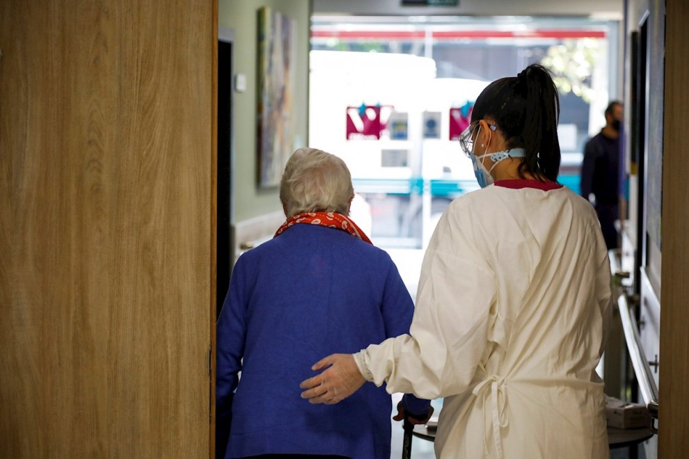 Una trabajadora de una residencia de mayores de Madrid ayuda a una paciente.