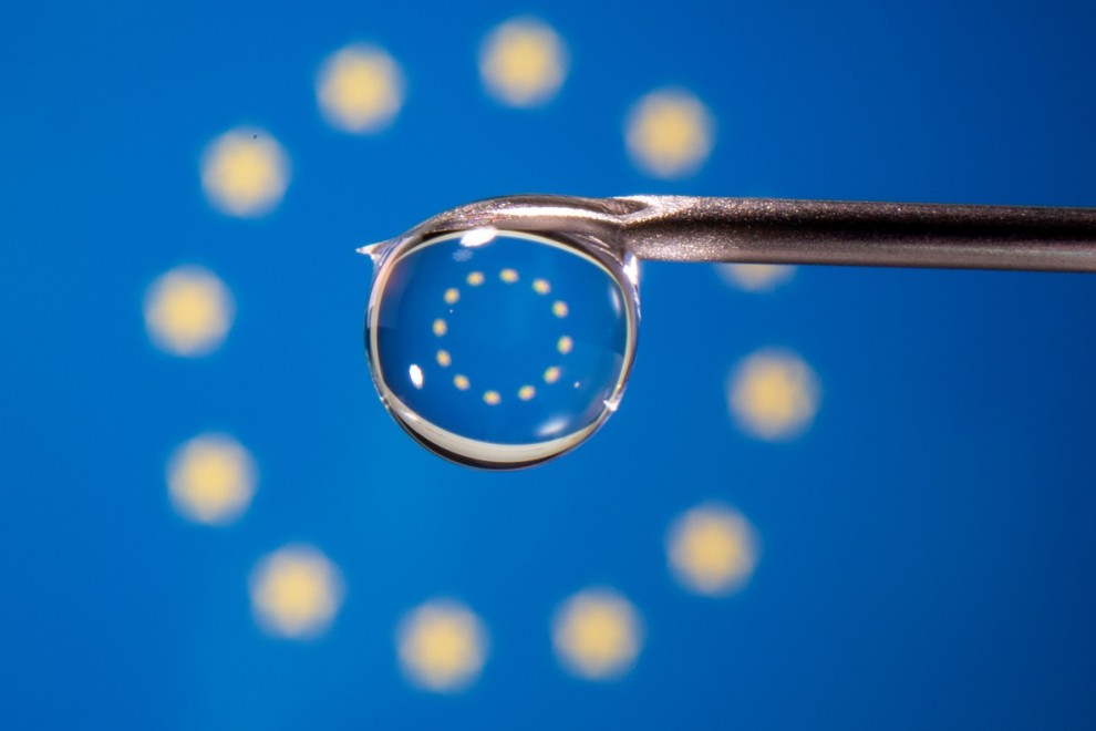 La bandera de la UE se refleja en la gota de una jeringuilla.