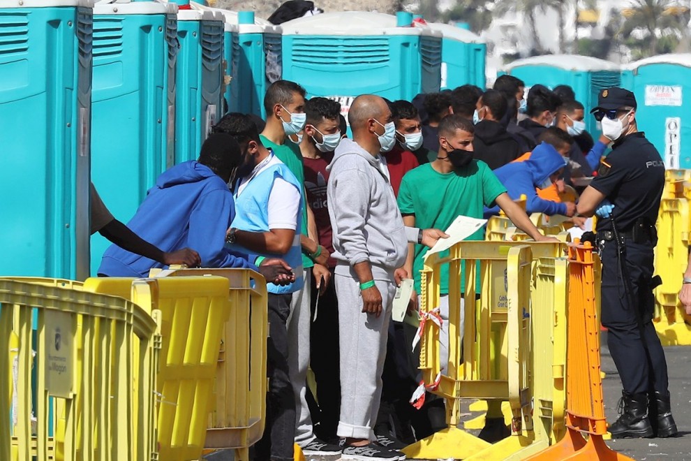 Varios migrantes esperan en el muelle de Arguineguín (Gran Canaria) a que les tomen las huellas dactilares y la filiación.