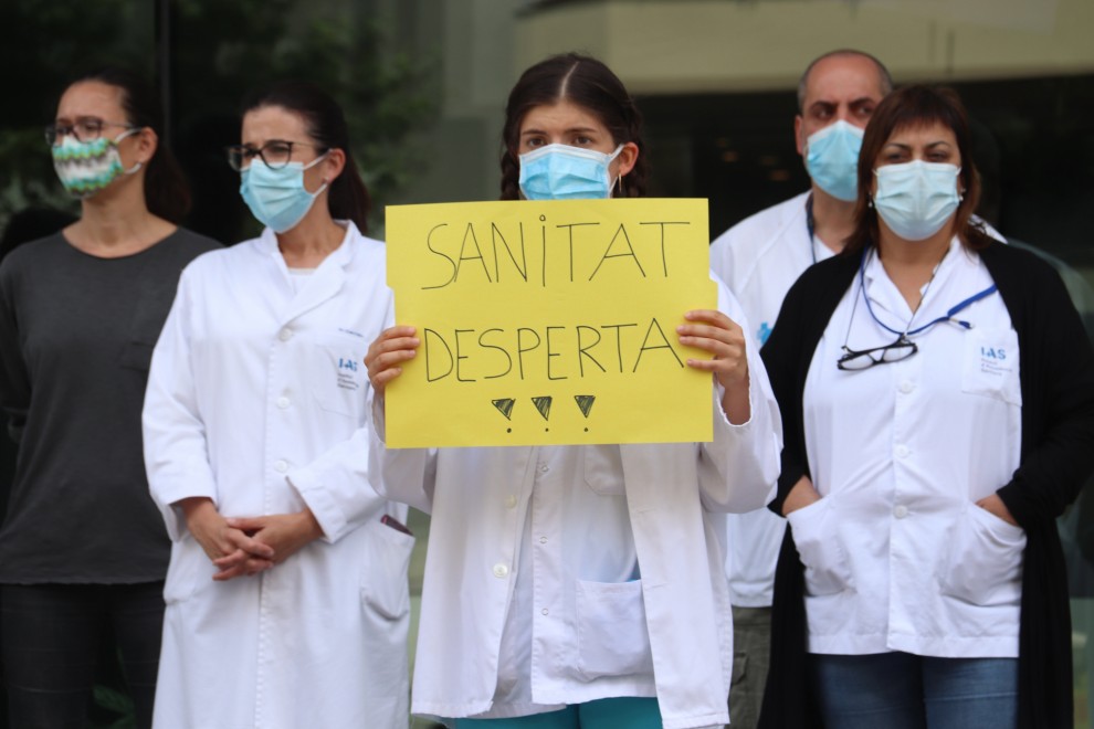 Una enfermera con una pancarta defendiendo la salud pública durante una movilización ante la Delegación de la Generalitat a Girona. ACN/Aleix Freixas