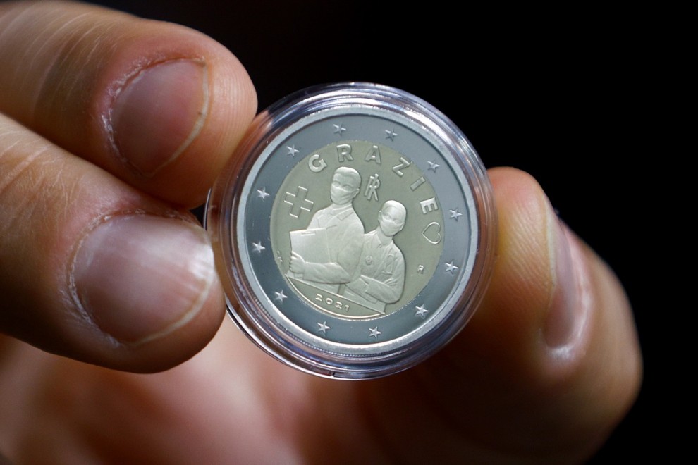 Un hombre muestra una moneda de dos euros que homenajea a los sanitarios.