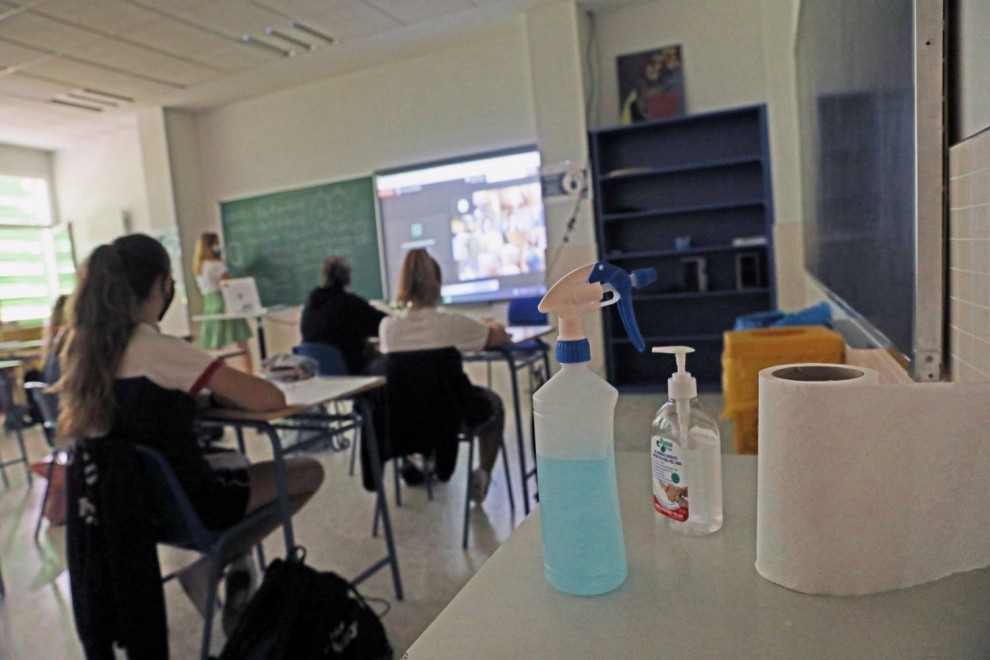 Productos desinfectantes colocados en los pupitres desde donde los alumnos atienden a las clases semipresenciales impartidas en el Colegio Ábaco, en Madrid.