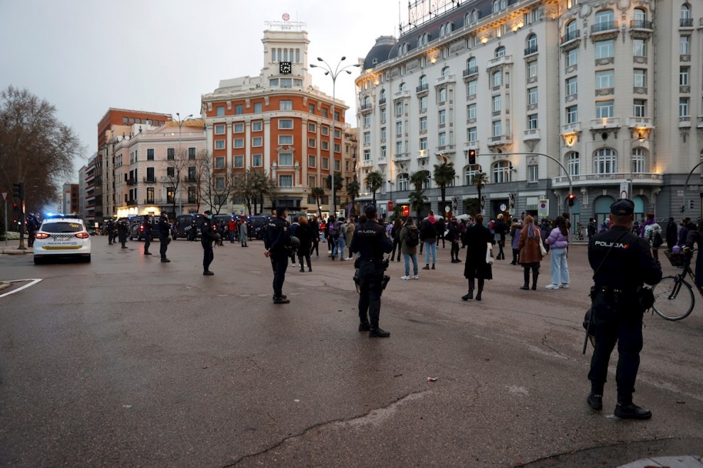 Efectivos policiales vigilan a asistentes a una sentada improvisada en la plaza de Neptuno de Madrid.