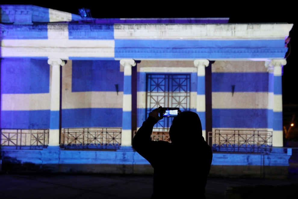 Un hombre toma fotografías frente al antiguo ayuntamiento de Nicosia, iluminado con la bandera griega que marca el 200 aniversario de la Guerra de Independencia de Grecia, en Nicosia, Chipre, el 25 de marzo de 2021.