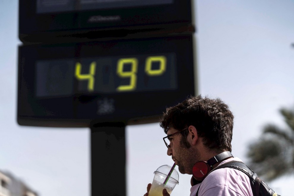 Un hombre toma una bebida junto a un termómetro de Córdoba en otra jornada marcada por la ola de calor en la que hay previsiones de que las temperaturas alcancen los 47 grados en el Valle del Guadalquivir.