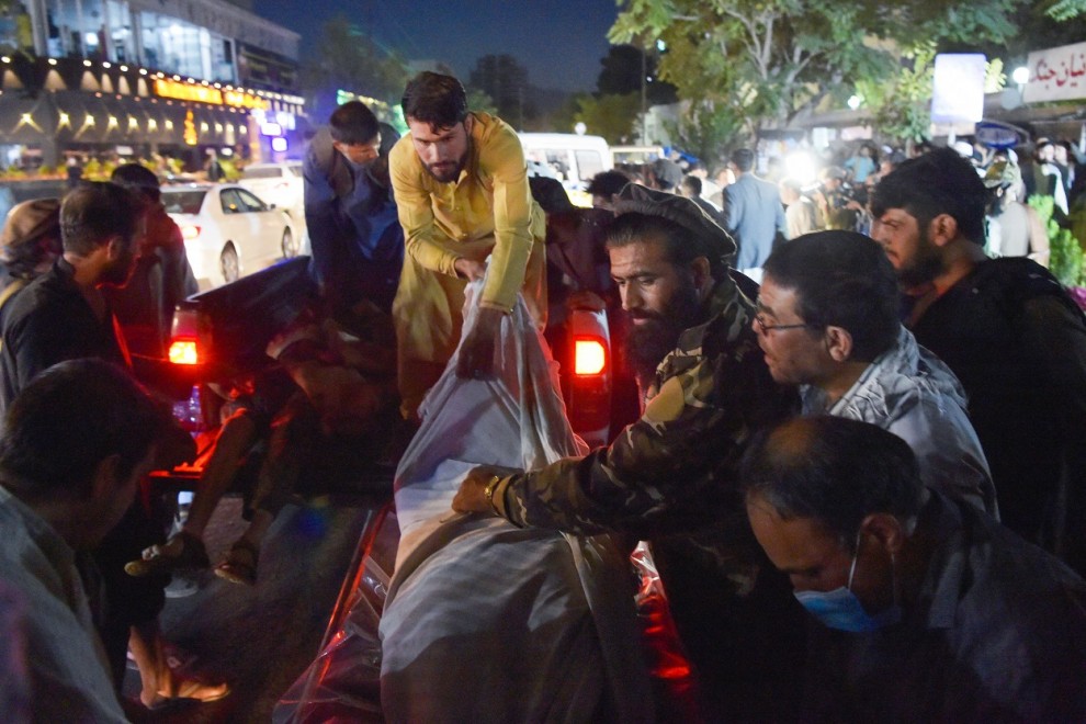 Voluntarios y personal médico descargan de una camioneta frente a un hospital el cuerpo de uno de los fallecidos en los atentados en Kabul. AFP/Wakil KOHSAR