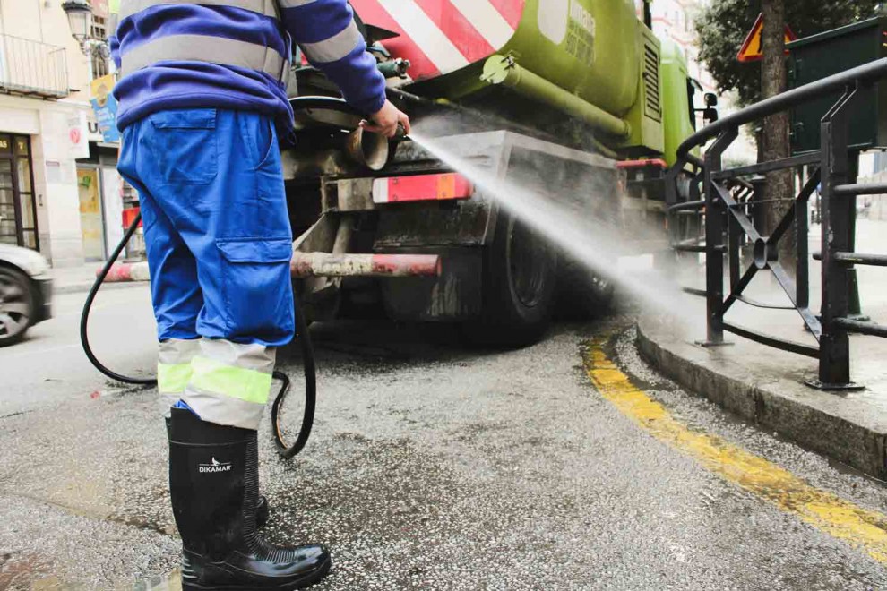 Un empleado del servicio de limpieza viaria baldea una calle de Málaga.