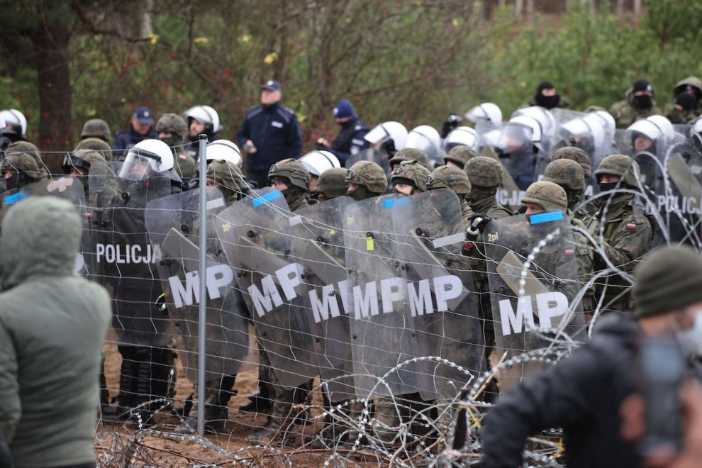 Una fotografía tomada el 8 de noviembre de 2021 muestra a agentes polacos observando a los migrantes en la frontera con Bielorrusia.