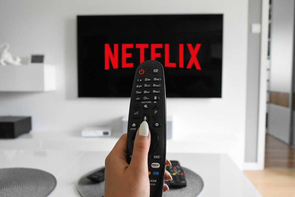Mando de televisión apuntando a una pantalla donde aparece el logo de Netflix.