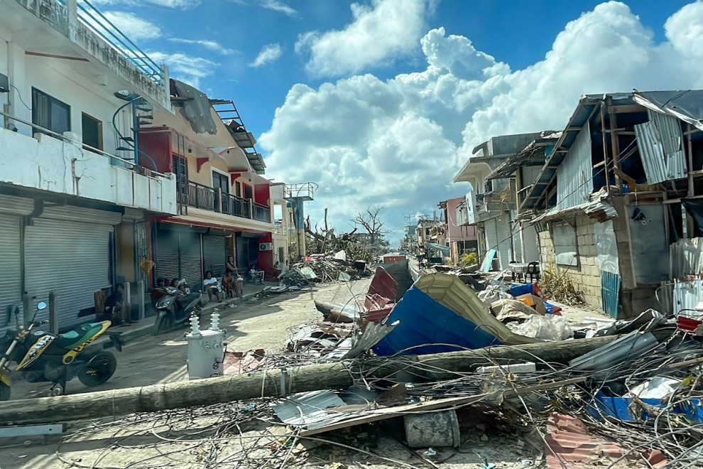 Un poste de luz y casas destruidas en Filipinas tras el paso del tifón Rai.