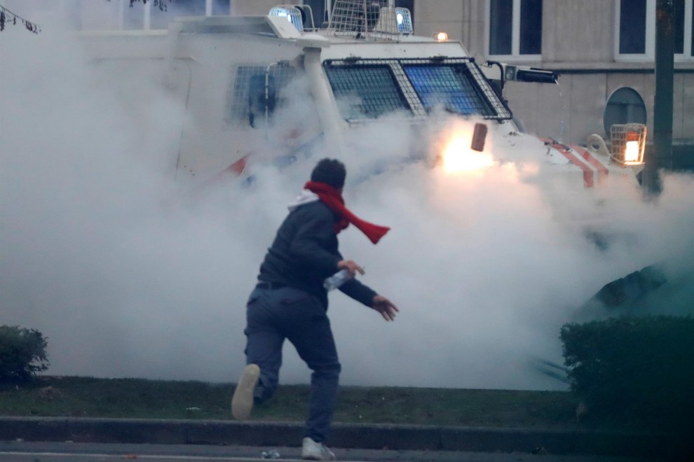 Un manifestante arroja un ladrillo a un vehículo policial durante los enfrentamientos tras una protesta contra las medidas europeas contra el coronavirus, en Bruselas.