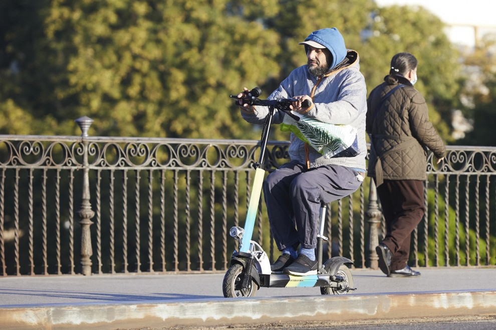 Una persona en su patinete, en Puente de Triana, en Sevilla.