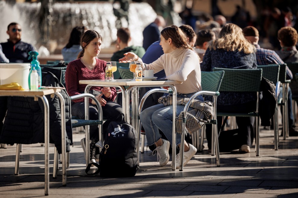 Varias personas disfrutan de un soleado día de invierno en una terraza en la ciudad de València.