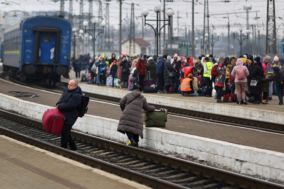 Refugiados ucranianos cruzan las vías del tren en la estación de Lviv.