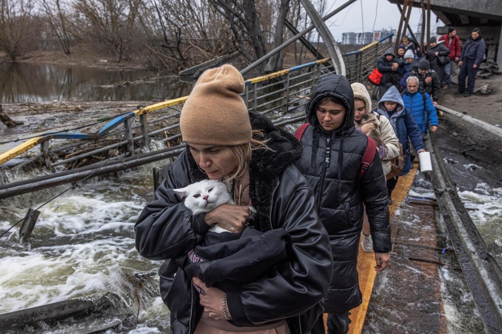 Una mujer con su gato cruza un puente destruido mientras los residentes huyen desde el frente de la ciudad de Irpín, en Kiev, este lunes 7 de marzo de 2022.