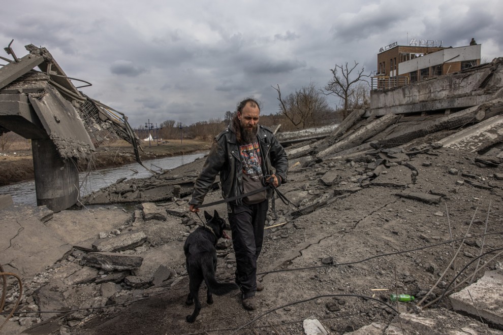 Un hombre con su perro cruza el puente destruido mientras huyen de la ciudad de primera línea de Irpin, región de Kiev (Kiev), Ucrania, 07 de marzo de 2022.