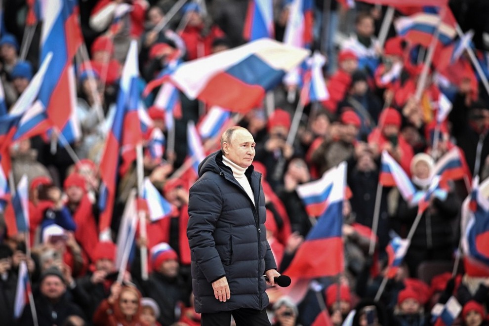 La multitud ondea banderas rusas mientras el presidente ruso Vladimir Putin camina para pronunciar un discurso durante un concierto celebrado para conmemorar el octavo aniversario de la anexión de Crimea por parte de Rusia en el estadio Luzhniki.