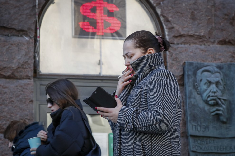 Una mujer rusa pasa junto a un panel que muestra el signo del dólar en una oficina de cambio en Moscú.