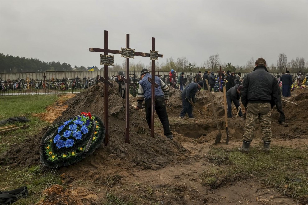 Varias personas entierran un cuerpo en el cementerio de Bucha (Ucrania) el 22 de abril de 2022.