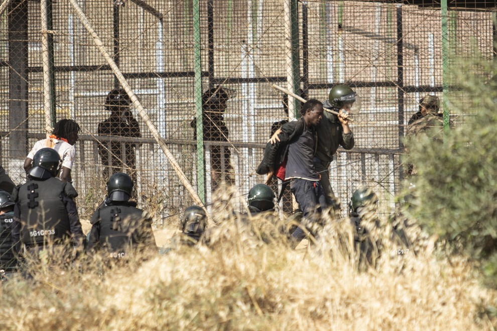 Un miembro de las fuerzas de seguridad marroquíes conduce desde suelo español a uno de los migrantes que logró saltar la valla de Melilla el pasado viernes.