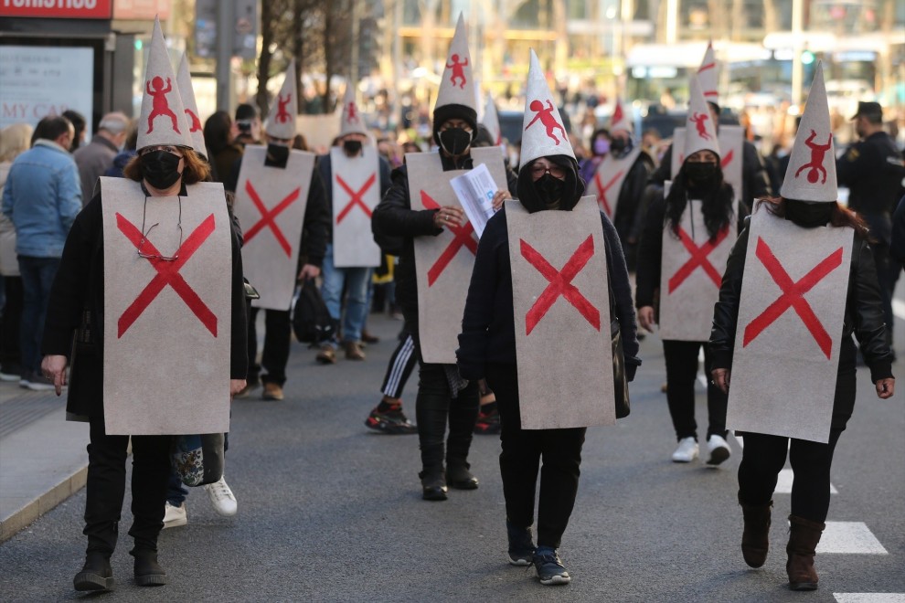 Varios manifestantes vestidos con petos tachados con cruces y capirotes blancos con niños dibujados, durante la manifestación en defensa de los menores tutelados, en el centro de Madrid el 29 de enero de 2022.