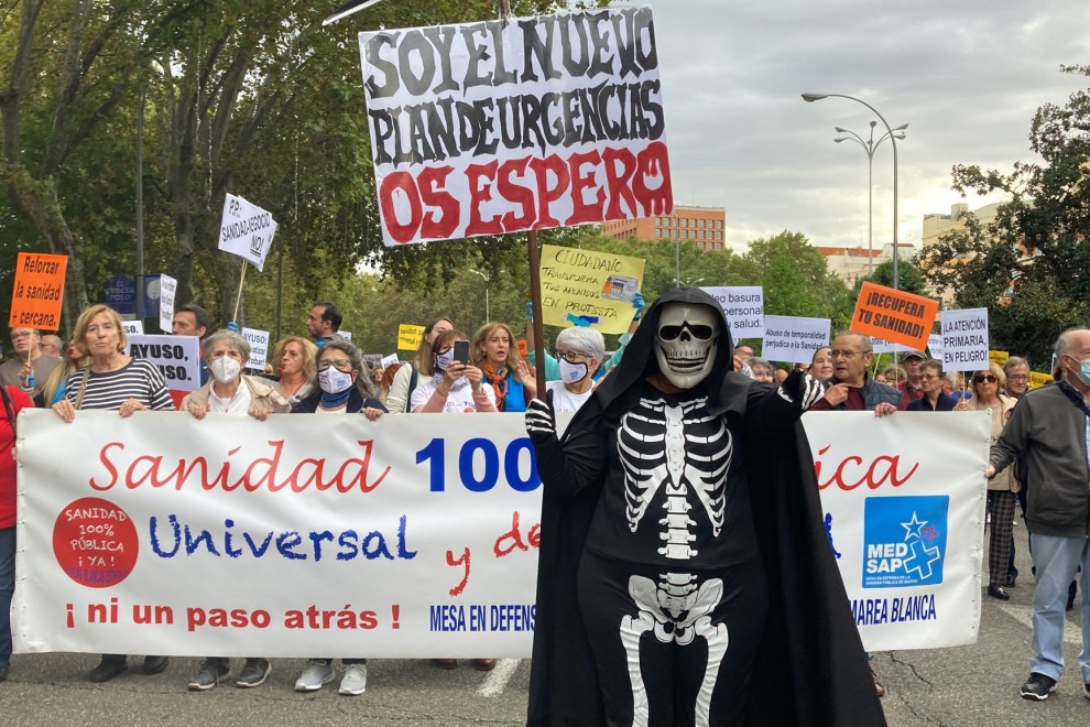 Una persona disfrazada de calavera sostiene una pancarta en la manifestación en Madrid contra la gestión sanitaria del Gobierno de Ayuso