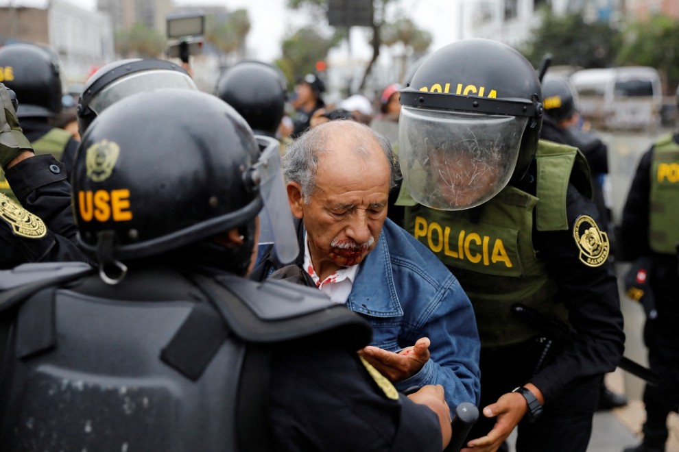 Un manifestante herido entre los agentes de policía apostados fuera de la Prefectura de Lima, mientras declaraba el presidente destituido Pedro Castillo. REUTERS/Alessandro Cinque