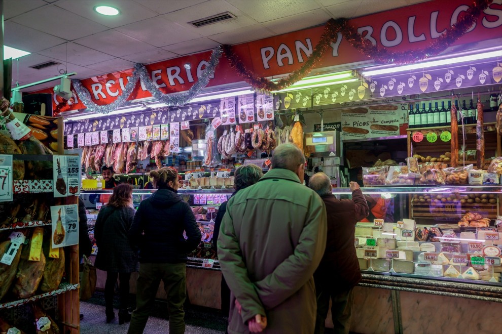 Varias personas esperan a ser atendidas en un puesto de productos alimentarios.