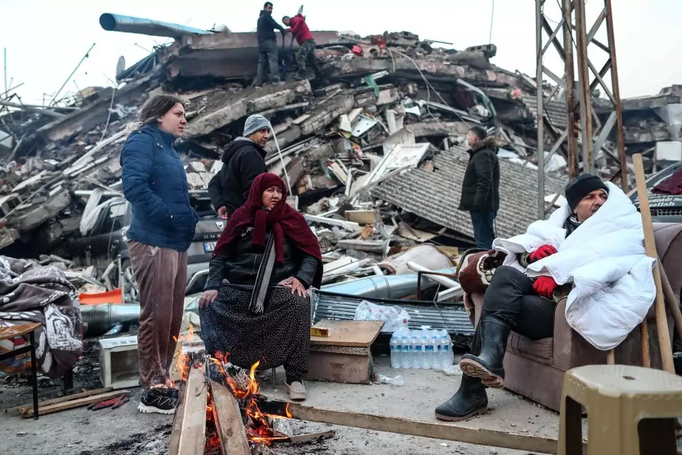 Varias personas intentan calentarse con fuego en las calles de Hatay (Turquía) después de quedarse sin casas, destruidas por el terremoto, este 8 de febrero de 2023.