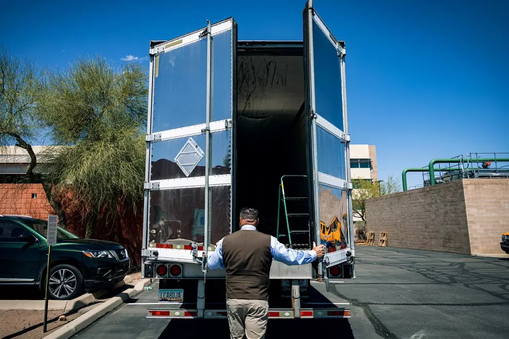Gene Hernández abriendo el trailer que se encuentra en el estacionamiento de su oficina con cientos de cajas de los casos de migrantes desaparecidos