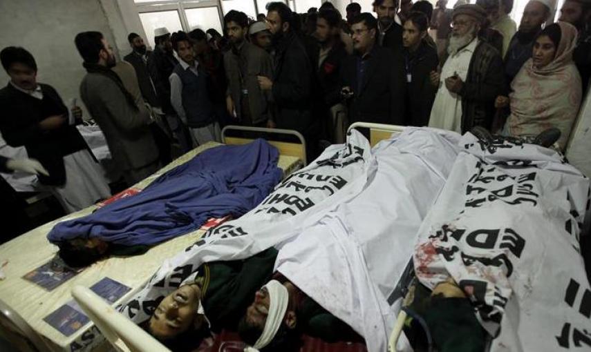Familiares y miembros de los servicios de emergencia congregados junto a los cadáveres de los alumnos asesinados en el ataque talibán contra una escuela militar. EFE/Arshad Arbab