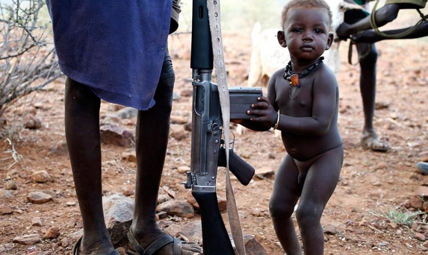 Un niño de Turkana se aferra a la escopeta de su padre, en un pueblo al noroeste de Kenia. /GORAN TOMASEVIC (REUTERS