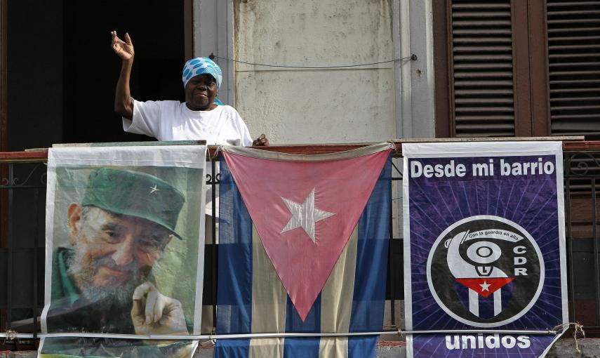 Una saluda desde el balcón de su vivienda adornado con una bandera cubana y la imagen del líder cubano Fidel Castro, en La Habana (Cuba). EFE/Alejandro Ernesto