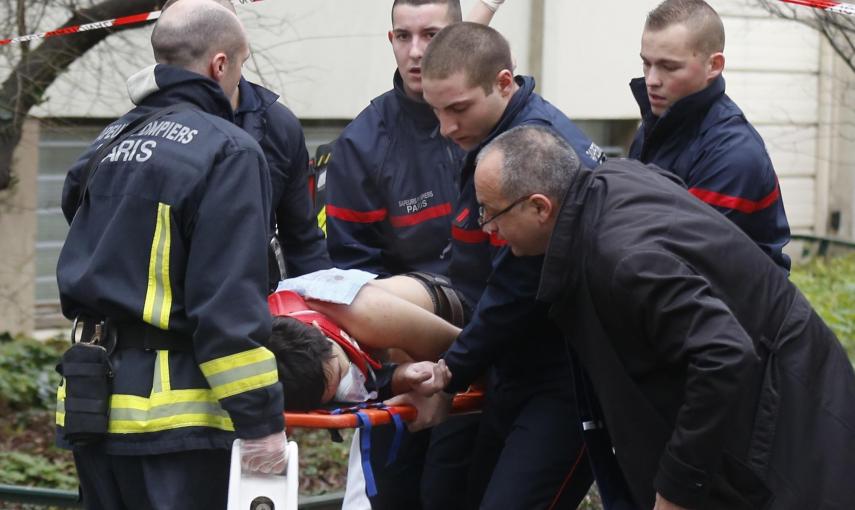 Unos bomberos trasladan en una camilla a uno de los heridos en el ataque al semanario satrico francés 'Charlie Hebdo'. REUTERS/Jacky Naegelen