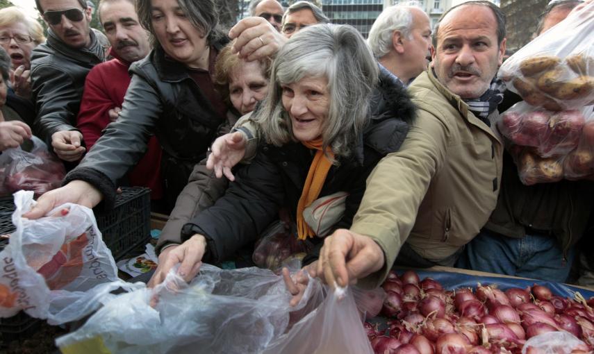 Un grupo de personas trata de recibir gratis cebollas y otras verduras ofrecidas por los agricultores en la plaza Syntagma (25 de enero 2012). REUTERS / Yannis Behrakis