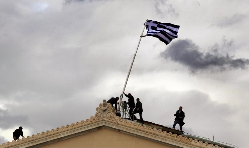 Empleados del Parlamento griego levanta el mástil de una bandera helena (18 de abril 2012). REUTERS / Yannis Behrakis