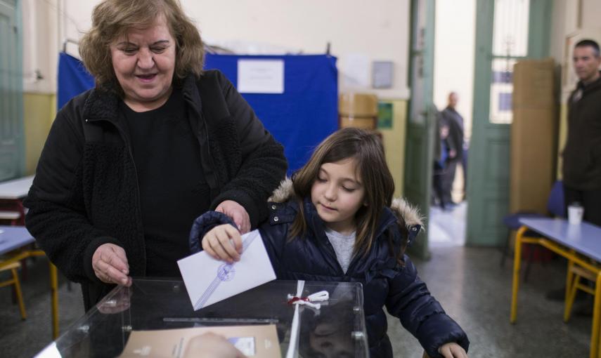 Una mujer deposita su voto con su hija en un colegio electoral de Atenas. REUTERS/Marko Djurica