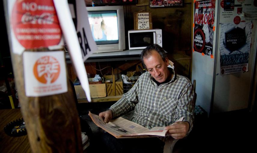 Un trabajador de Coca-Cola en Fuenlabrada lee el periódico en el interior de campamento donde llevan un año exigiendo la reapertura de la fábrica. -JAIRO VARGAS
