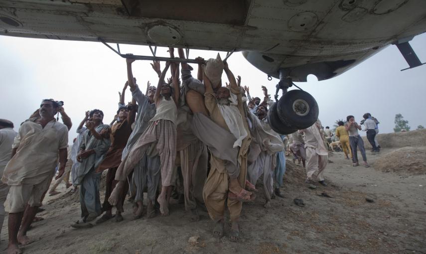 Víctimas de las inundaciones Marooned, en Paquistán, tratan de agarrarse a las barras laterales de un helicóptero del Ejército que transportaba alimentos para los damnificados (7 de agosto de 2010). REUTERS / Adrees Latif