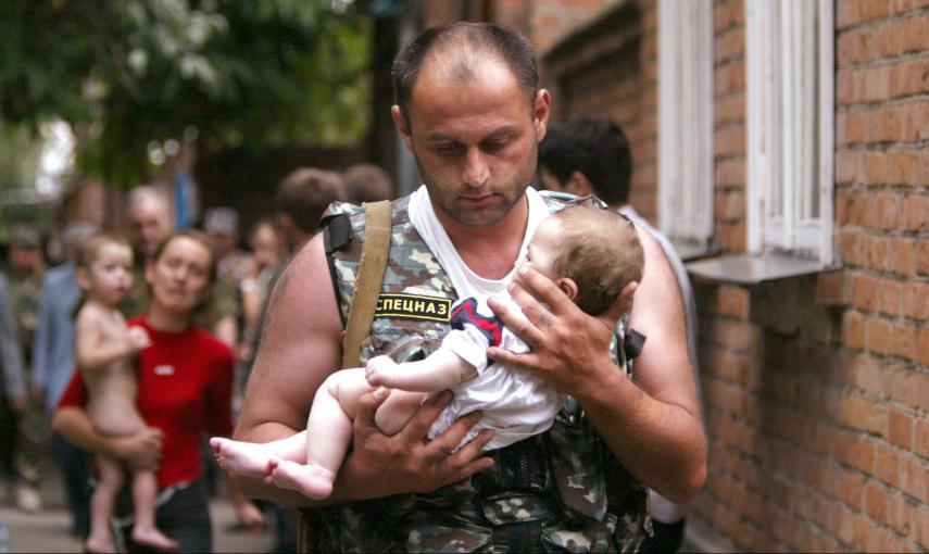 Un oficial de la policía rusa lleva un bebé liberado en la escuela de en la ciudad de Beslan, en la provincia de Osetia del Norte, cerca de Chechenia, tras el asalto de hombres y mujeres enmascarados fuertemente armados (2 de septiembre de 2004). REUTERS