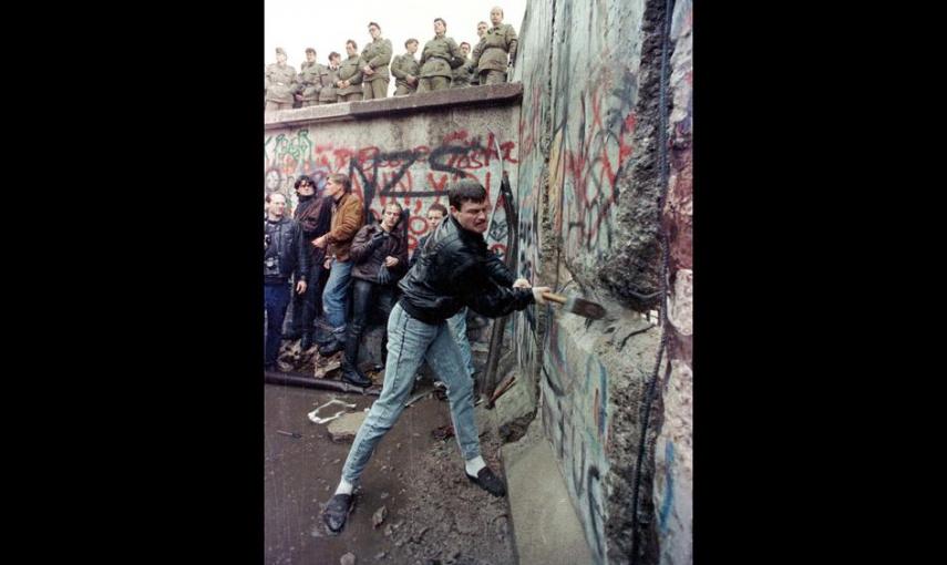 Un alemán golpea con un mazo el Muro de Berlín, bajo la mirada de los guardias de frontera del lado oriental de la ciudad (11 de noviembre de 1989). REUTERS / David Brauchli