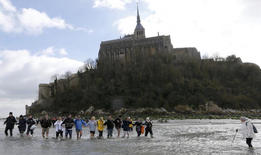Los turistas caminan con las aguas bajas alrededor de la abadía del Mont Saint-Michel, en Normandía. REUTERS / Pascal Rossignol