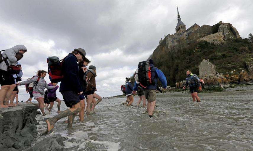 El guía Sebastien Daligault acompaña a un grupo de visitantes con el agua hasta las rodillas durante un recorrido a pie por hasta el Mont Saint-Michel, en la costa francesa de Normandía. REUTERS / Pascal Rossignol
