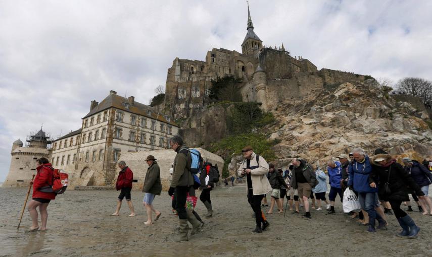 Una guía acompaña a un grupo de turistas que abandonan la abadía del Mont Saint-Michel, antes de que quede rodeado de agua por la marea alta.. REUTERS / Pascal Rossignol