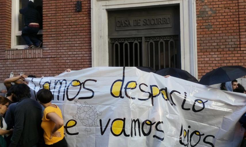 Varios activistas tapan la puerta mientras otros entran en el edificio que han okupado en el centro de Madrid.- ALEJANDRO TORRÚS