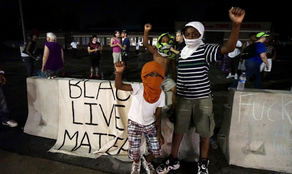 Tres manifestantes jóvenes, entre ellos un niño de tres años de edad, protestan fuera del departamento de policía de Ferguson. REUTERS