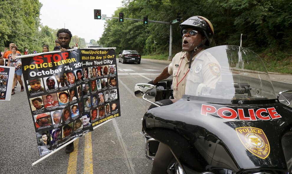 Un oficial de policía del condado de San Luis mantiene conversaciones desde su moto con los manifestantes en una marcha de protesta en Ferguson. REUTERS