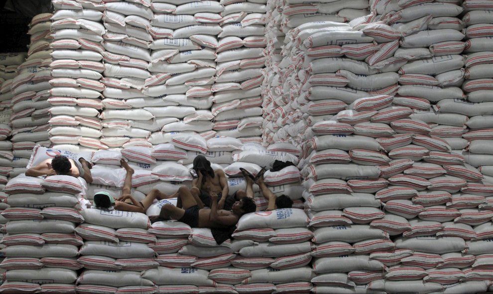 Trabajadores descansan encima de sacos de arroz apilados dentro de un almacén de la Autoridad Nacional de Alimentos en la ciudad de Taguig, al sur de Manila, 25 de agosto de 2015. REUTERS/Romeo Ranoco