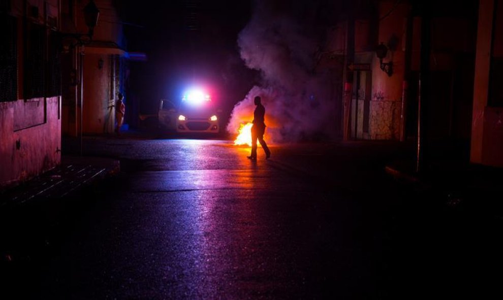 Policías dominicanos apagan una barricada encendida en protesta por el extenso apagón, debido a que el 85% del país se encuentra sin energía eléctrica tras el paso de la tormenta tropical Erika hoy, viernes 28 de agosto de 2015, en la zona colonial de San