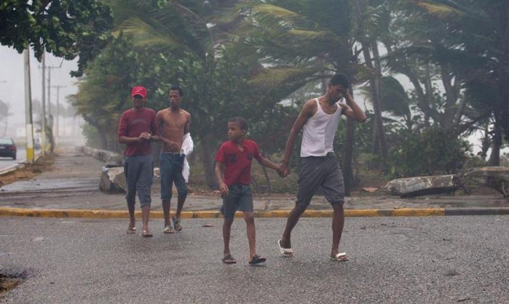 Jóvenes caminan bajo la lluvia durante la llegada de la tormenta tropical Erika hoy, viernes 28 de agosto de 2015, en Santo Domingo (República Dominicana). El centro de la tormenta tropical Erika se aproxima hoy al país mientras deja fuertes lluvias en Pu